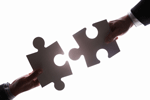 Two hands joining together two oversized jigsaw pieces